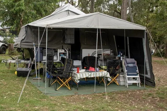 camper trailer that has been unpacked with tent setup and all cooking and seating presented